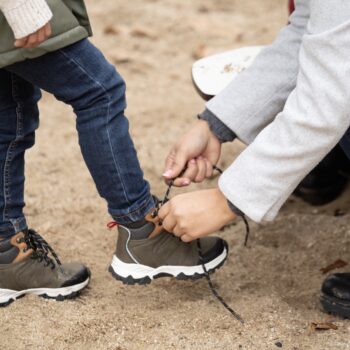 mama leagă șireturile copilului